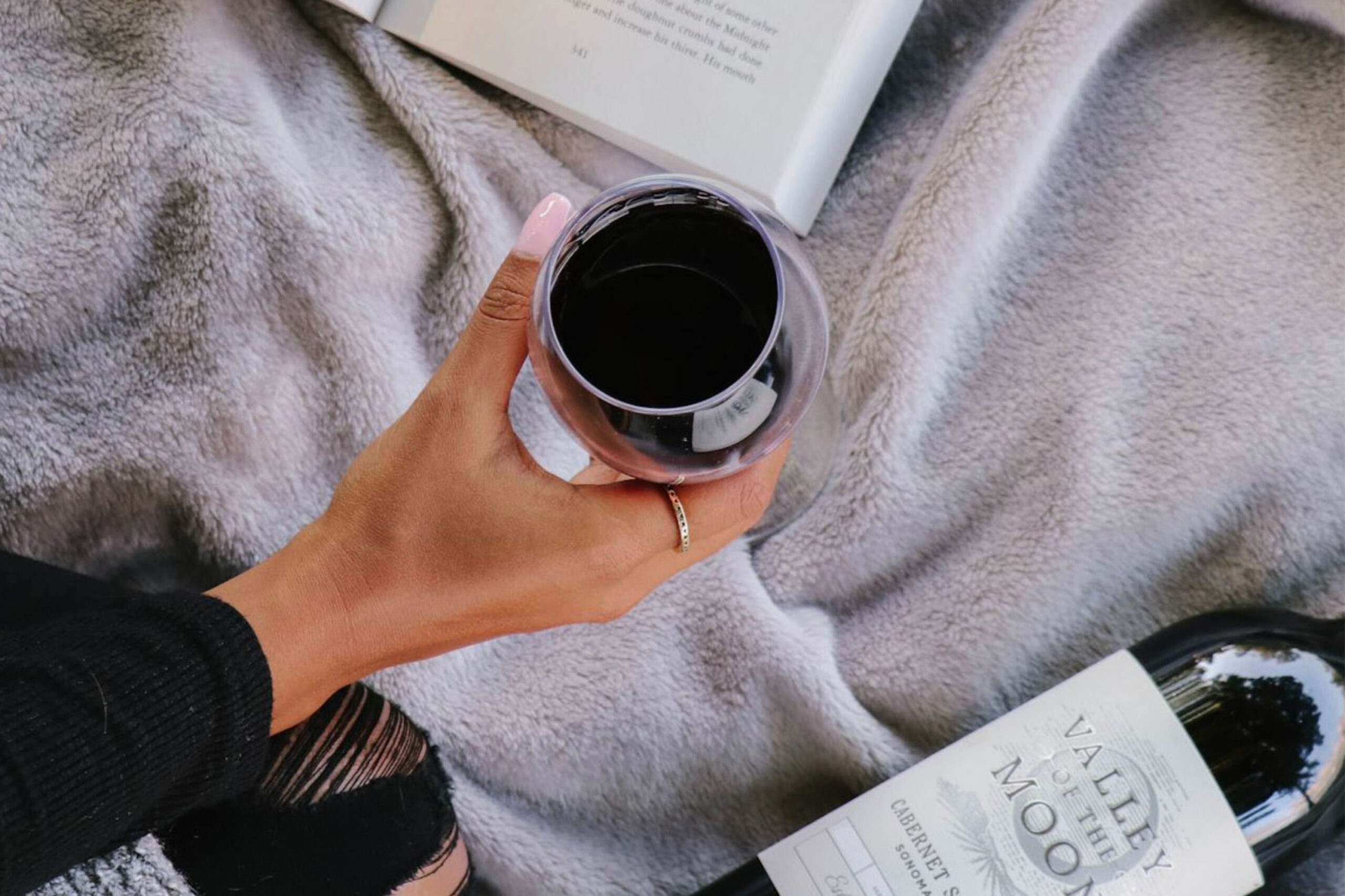 woman holding glass of Valley of the Moon Cabernet Sauvignon Reading a book